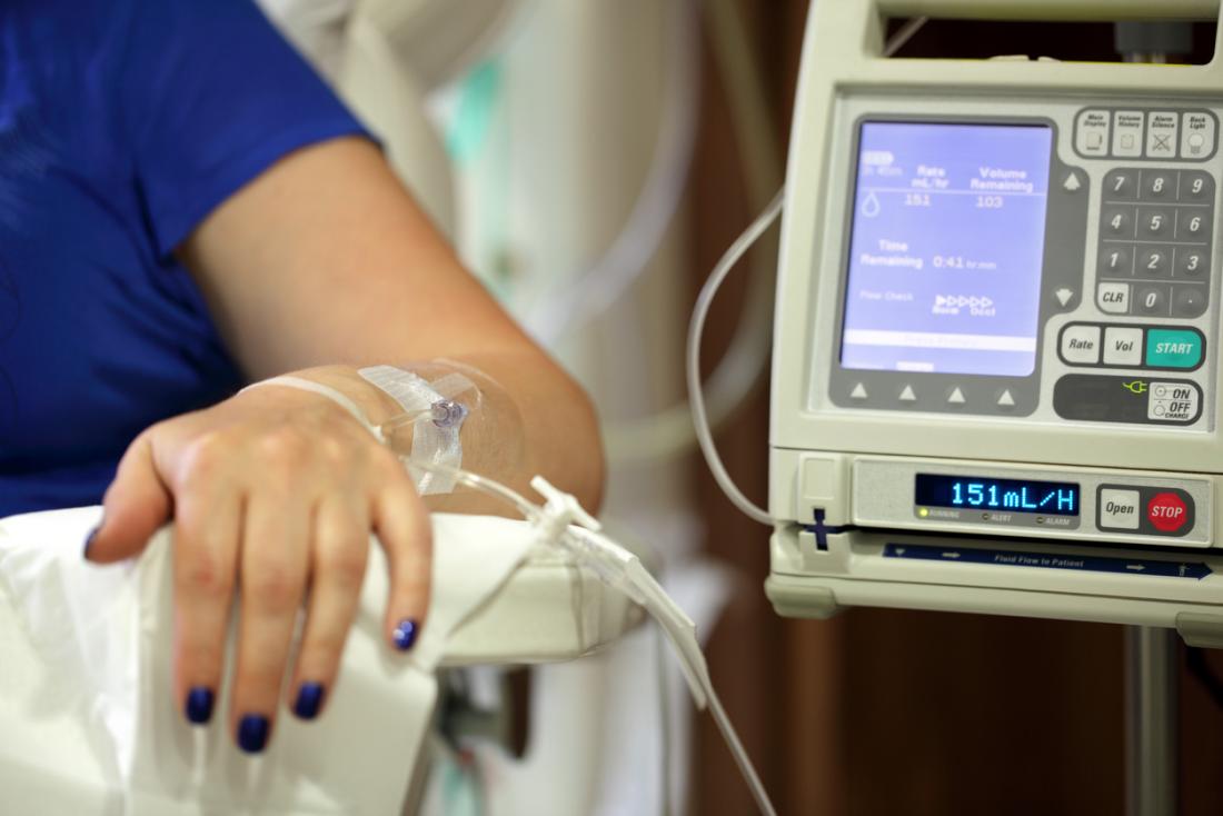 A woman undergoing chemotherapy sitting in a chair with an intravenous drip.