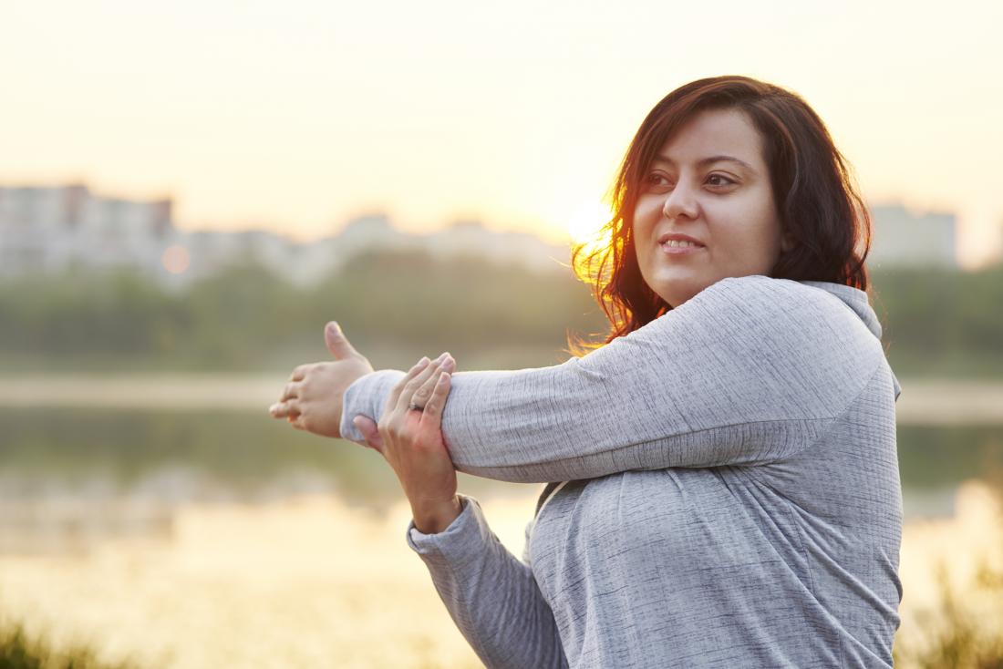 young woman with rapid weight gain doing stretching exercises outside