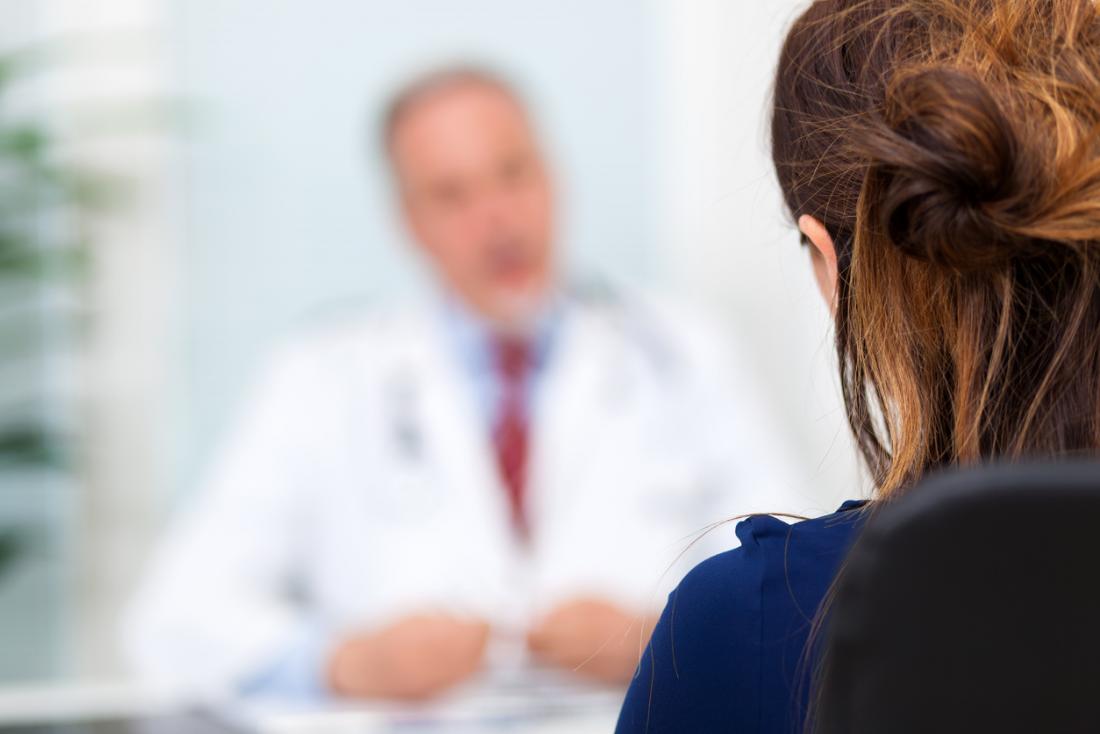 A doctor in the background speaking to a patient in the foreground