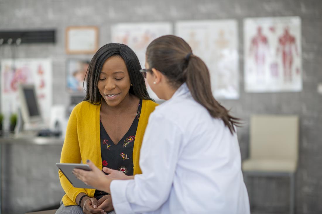 a doctor showing a patient information on an ipad