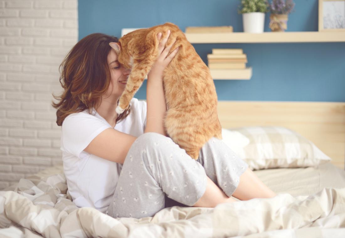 a woman in bed cuddling her cat
