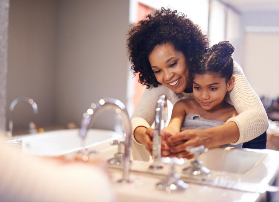 mother helping her daughter wash her hands