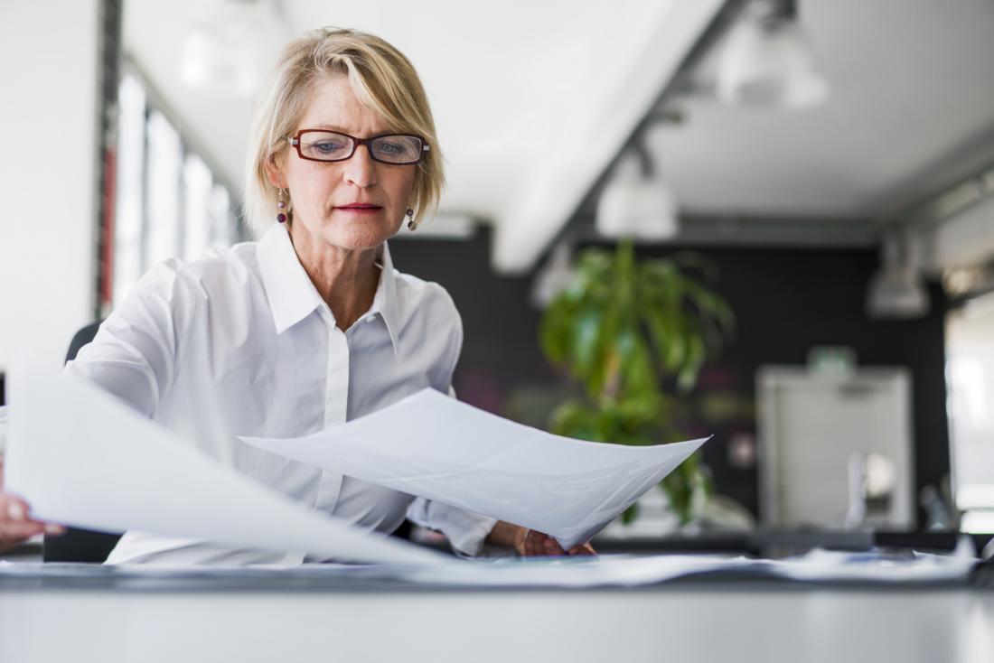 older lady juggling paper at work