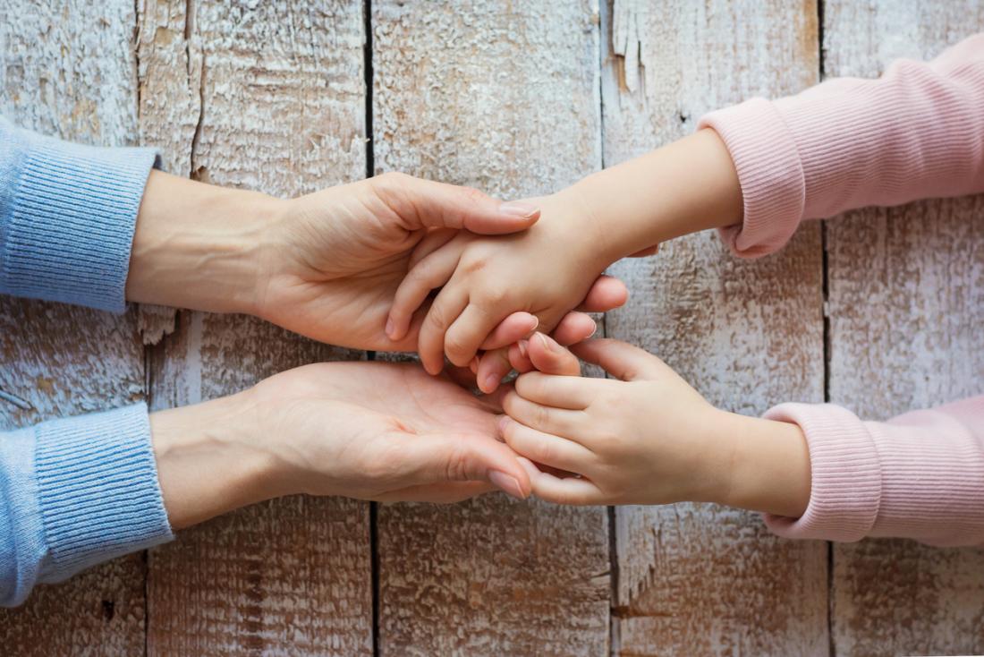 mother and daughter holding hands across a table