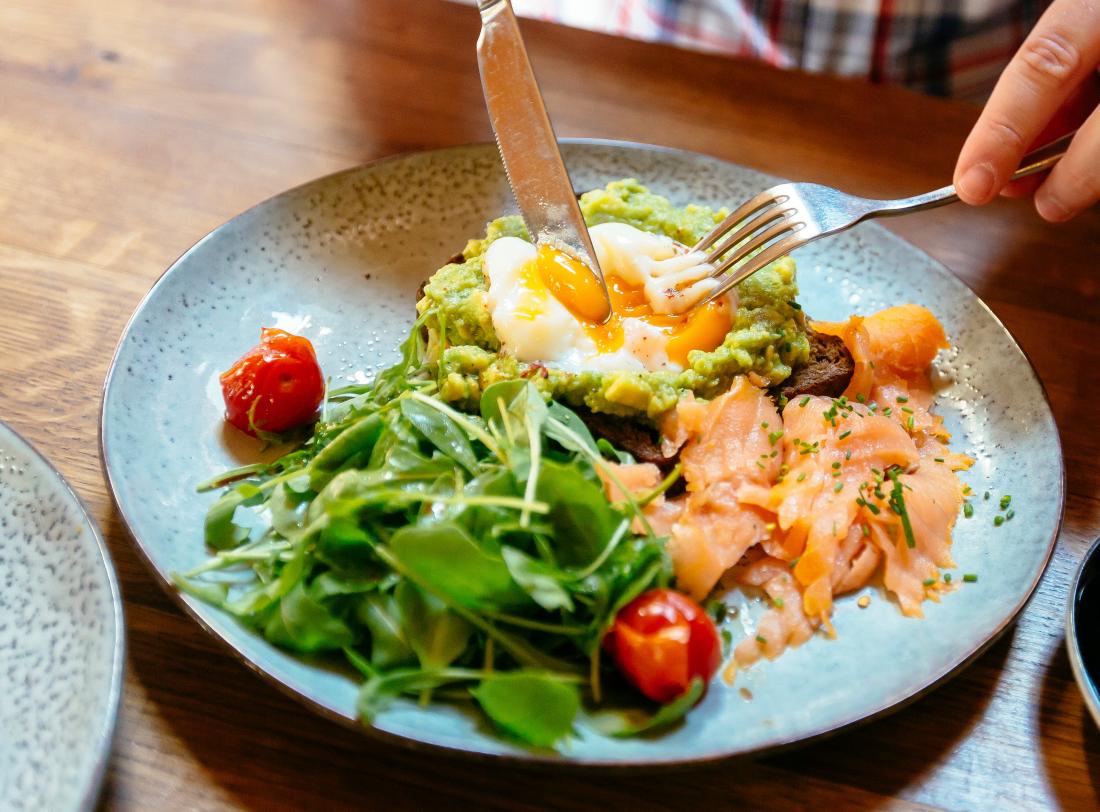a person eating salmon, eggs and Avocados as part of their ulcerative colitis diet plan