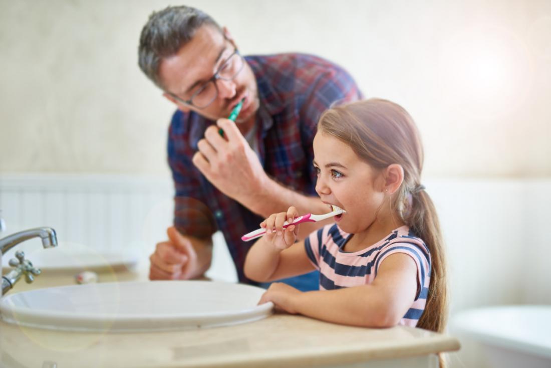 father and daughter cleaning teeth