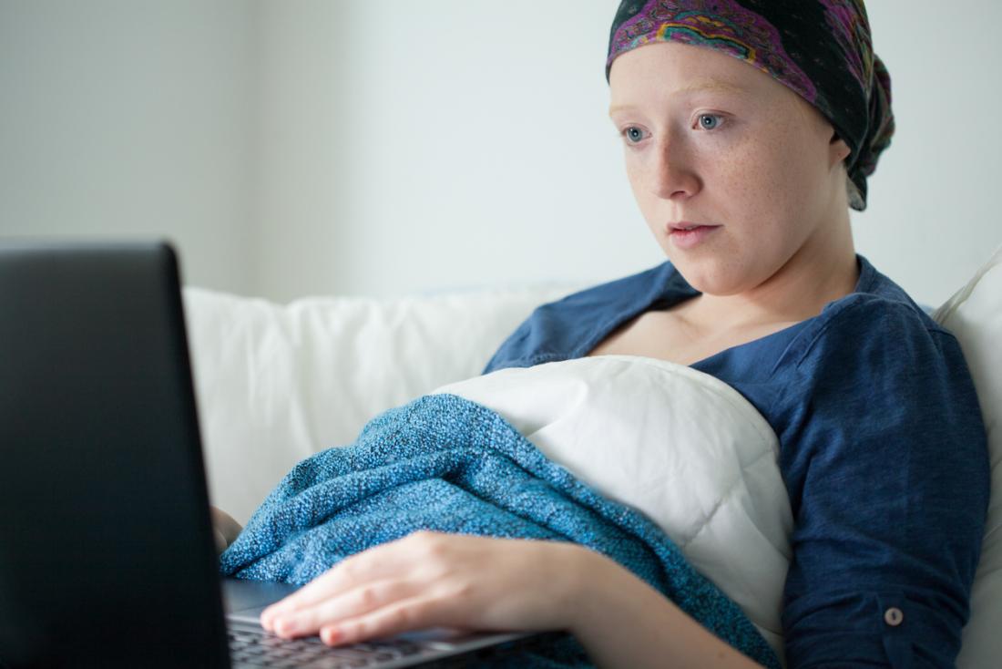 woman with cancer looking at a computer in bed