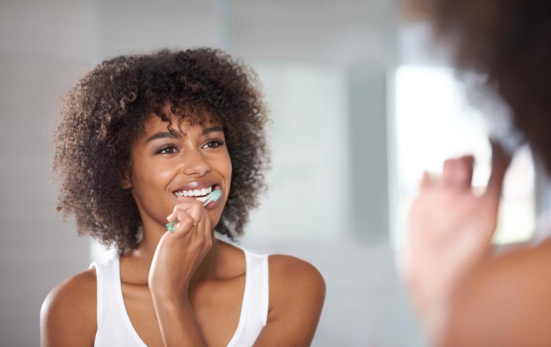 lady brushes her teeth in the mirror