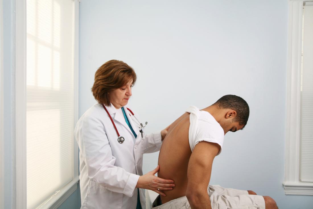 doctor diagnosing a young man with back pain