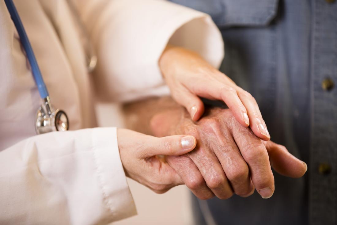 Female doctor holding old persons hand