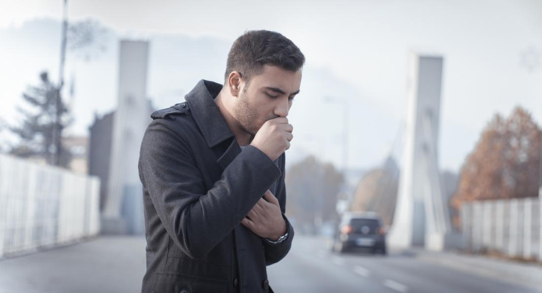 Man coughing in street.