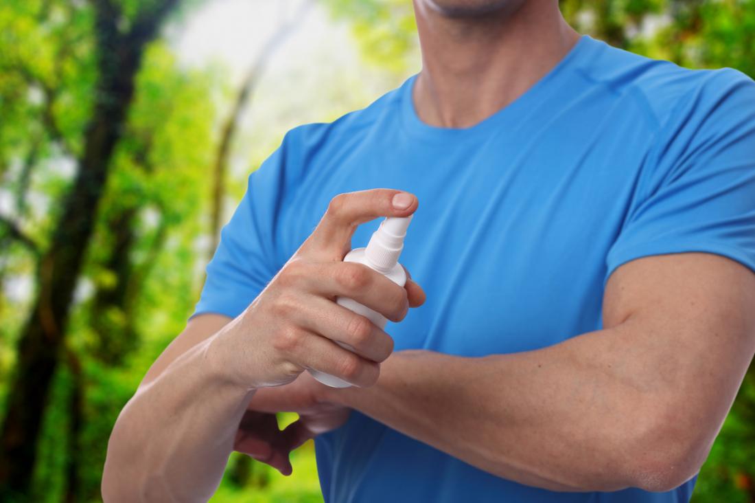 Man spraying insect or mosquito repellent on arm.