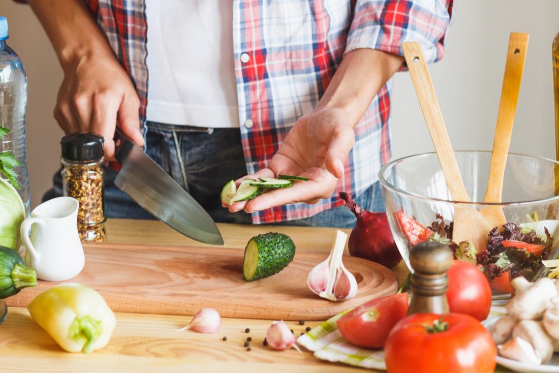 person slicing cucumber to make salad