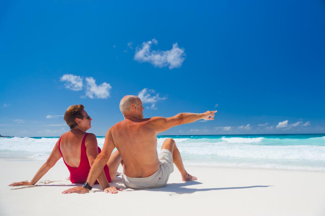An older couple sunbathing on a beach