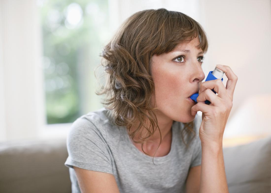 Woman with asthma using inhaler.
