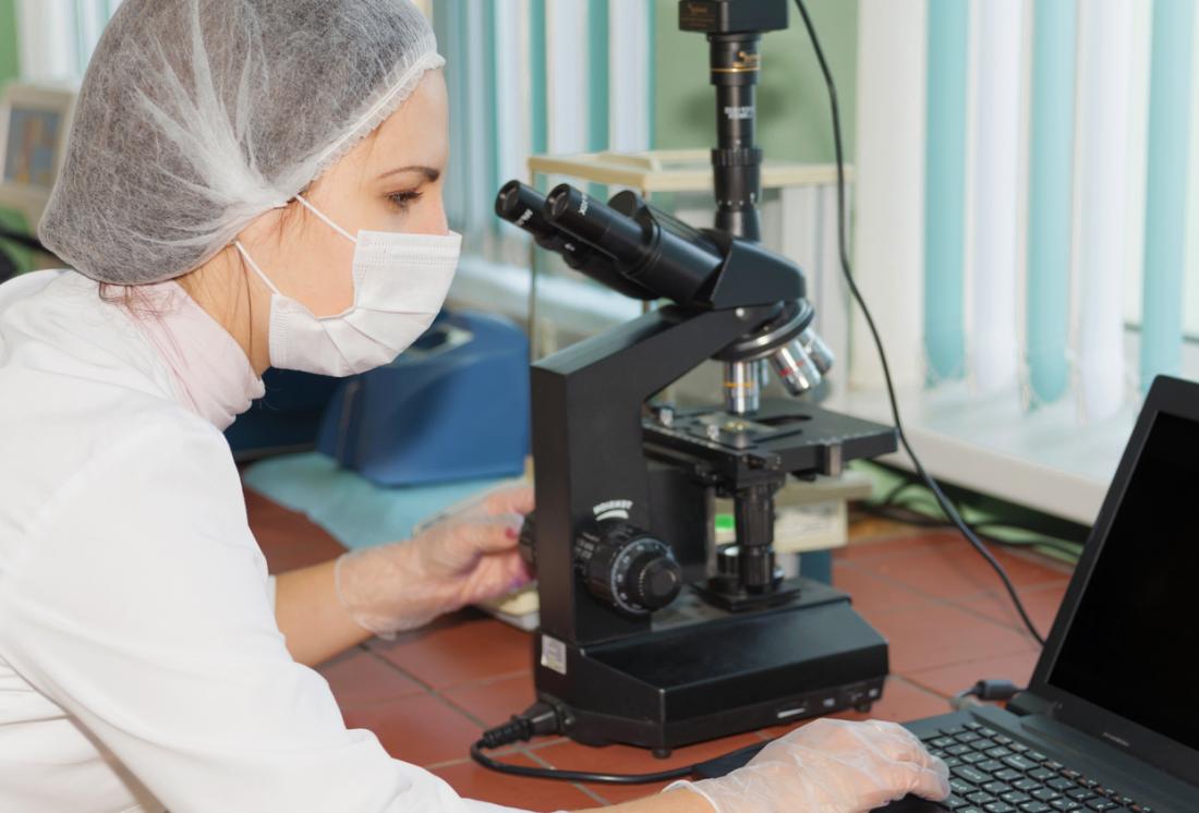 scientist with microscope and laptop