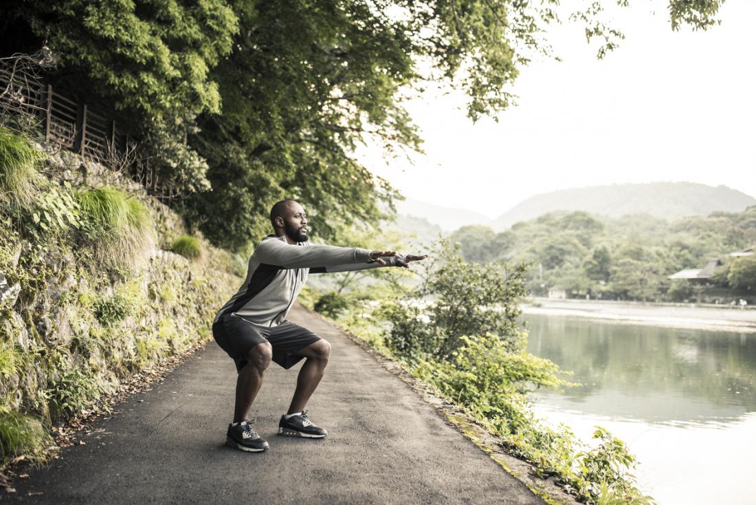 man doing a squat on a trail