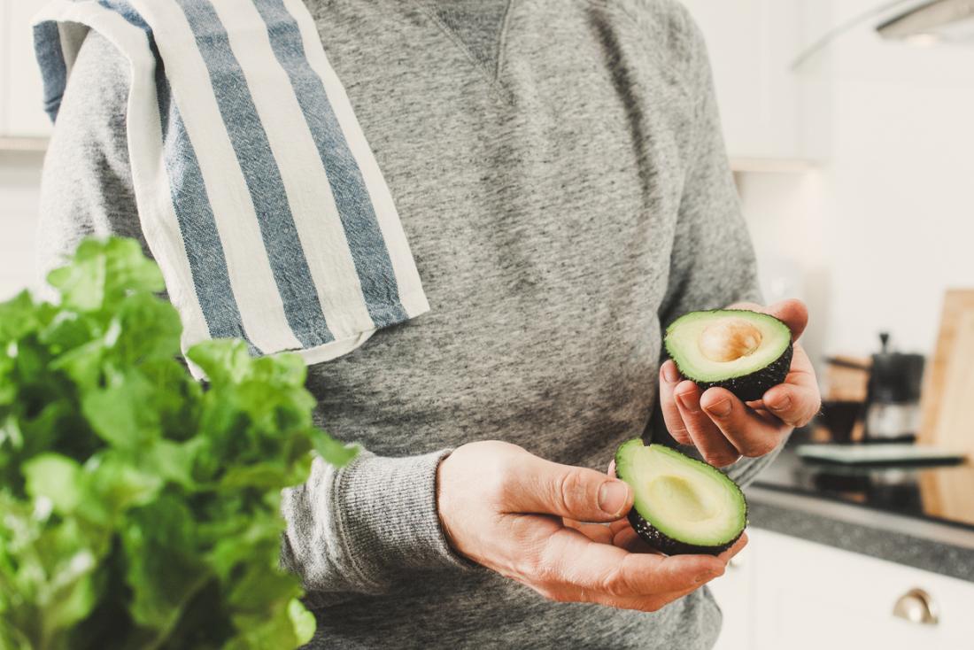 man holding avocado while cooking