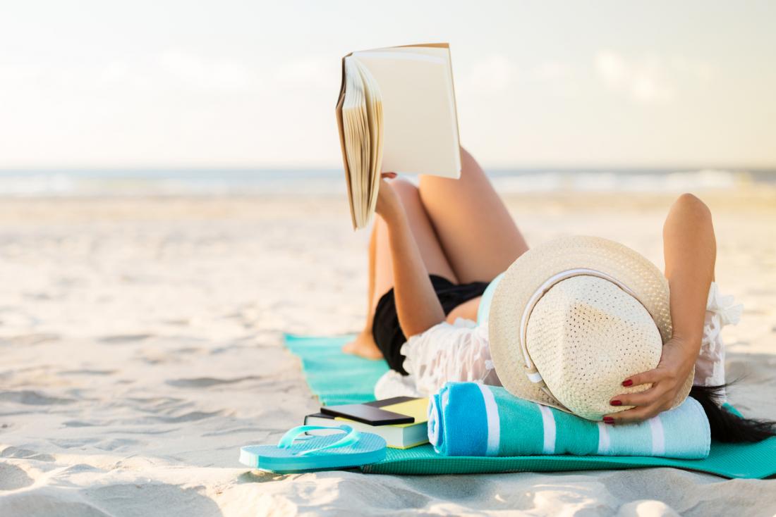 woman sunbathing and reading a book at the beach
