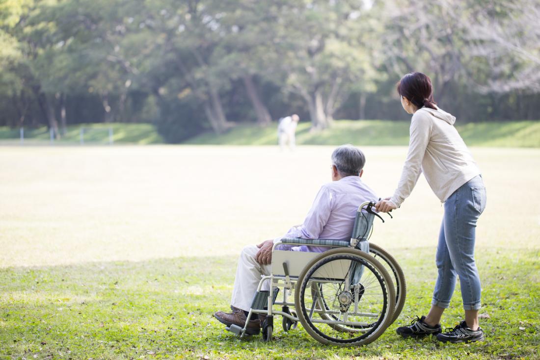 Elderly man in wheelchair outside with carer.