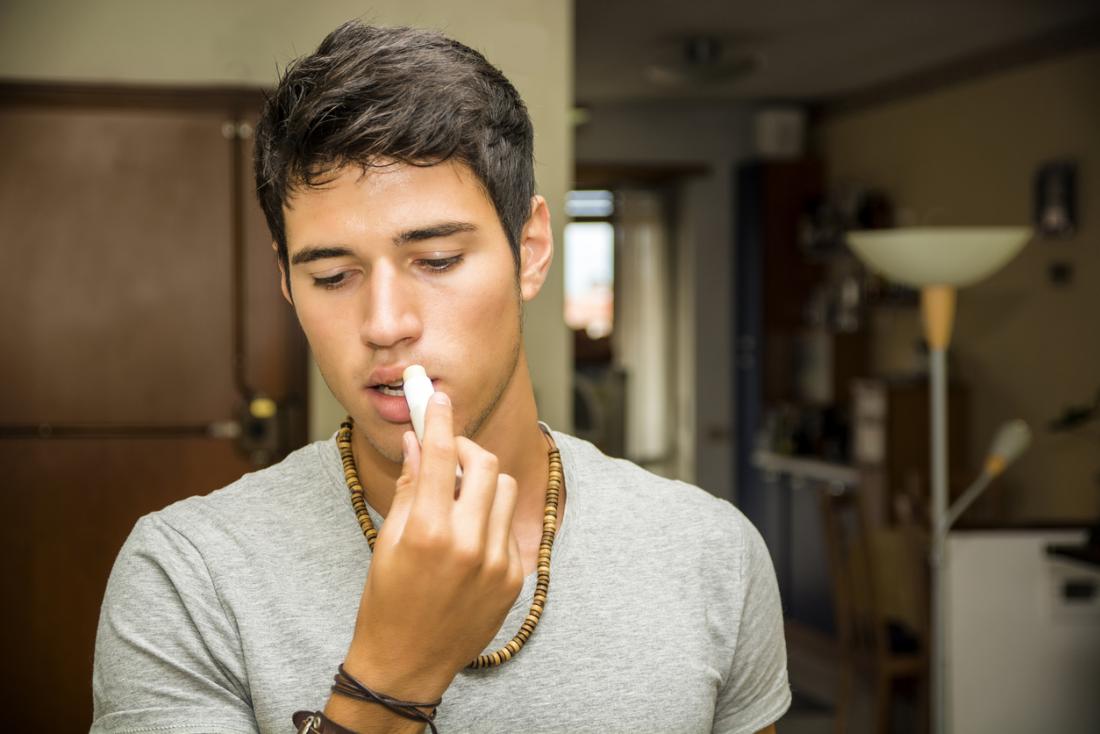 Young man applying lip balm.