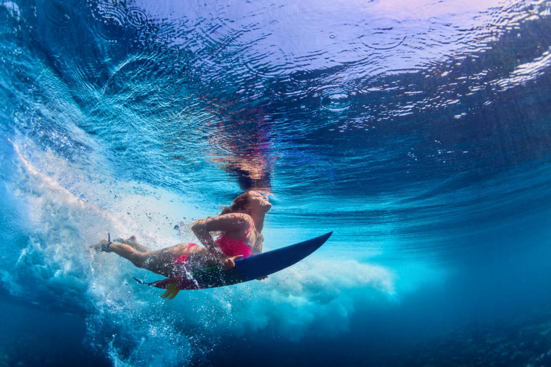 girl underwater on a surfboard