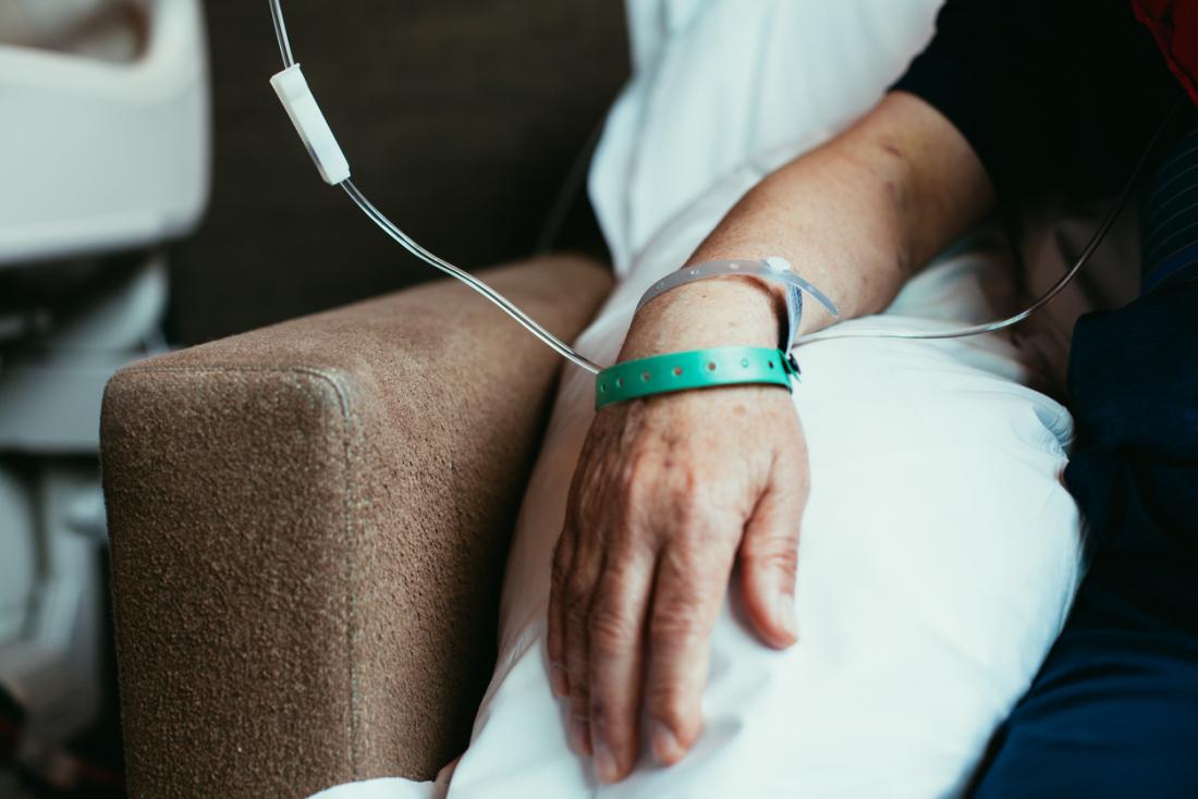 Senior mans hand in chair as he receives chemotherapy.