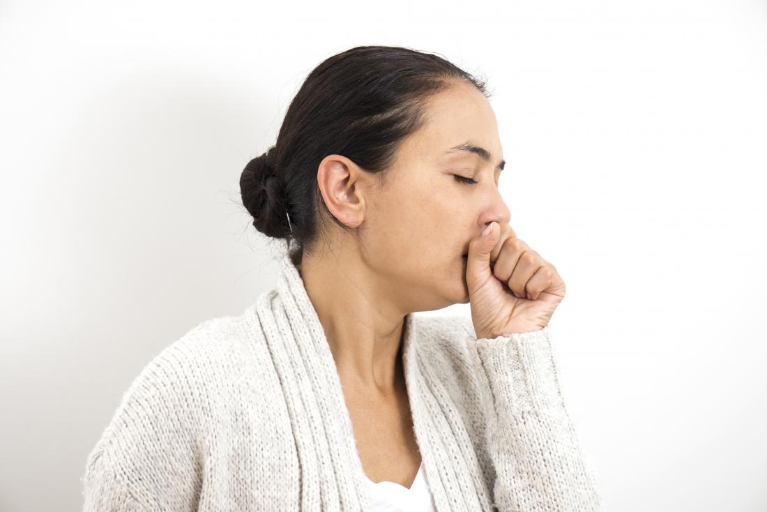 Woman holding her hand over her mouth and coughing