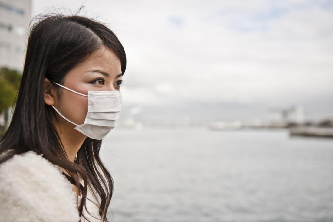 Woman wearing a pollution mask over her mouth on seafront.