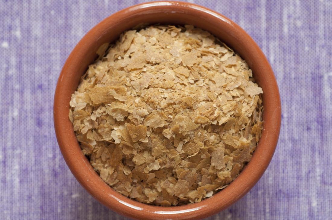 A bowl with nutritional yeast flakes, a plant-based source of B-12.