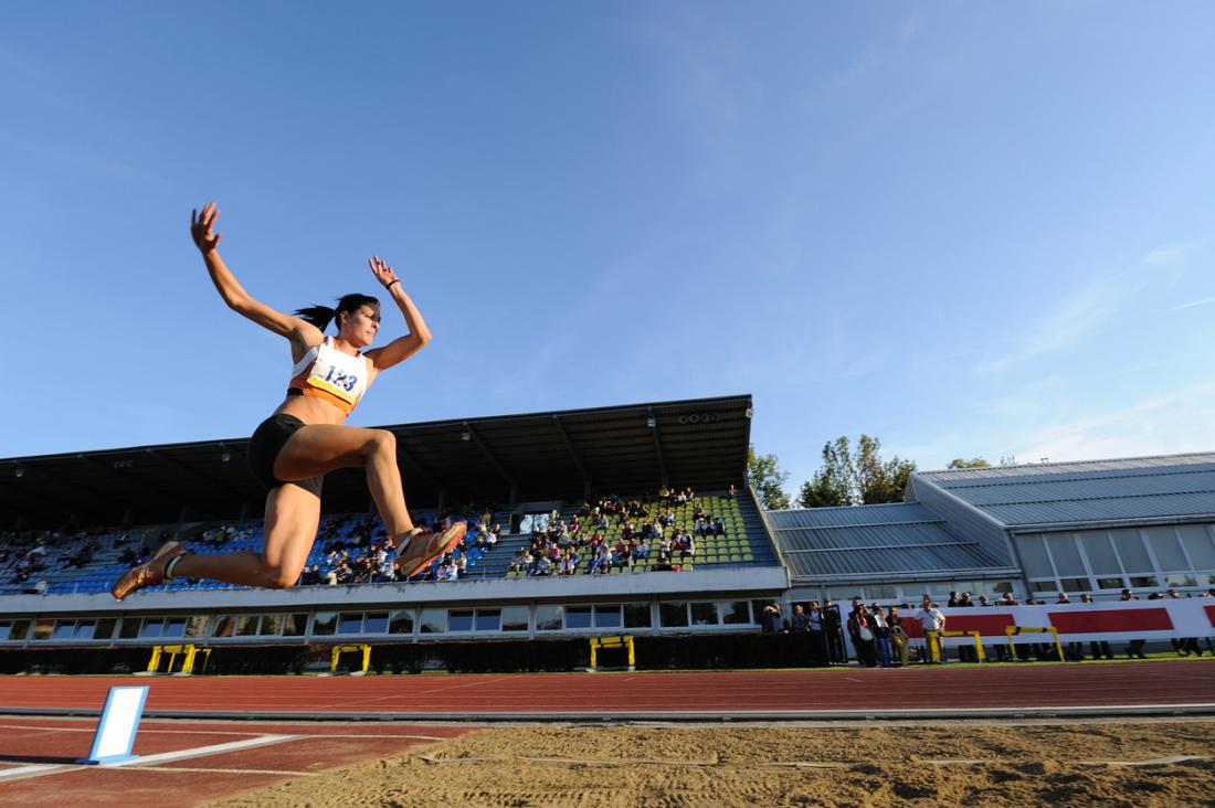 Female long jumper leaping into sand