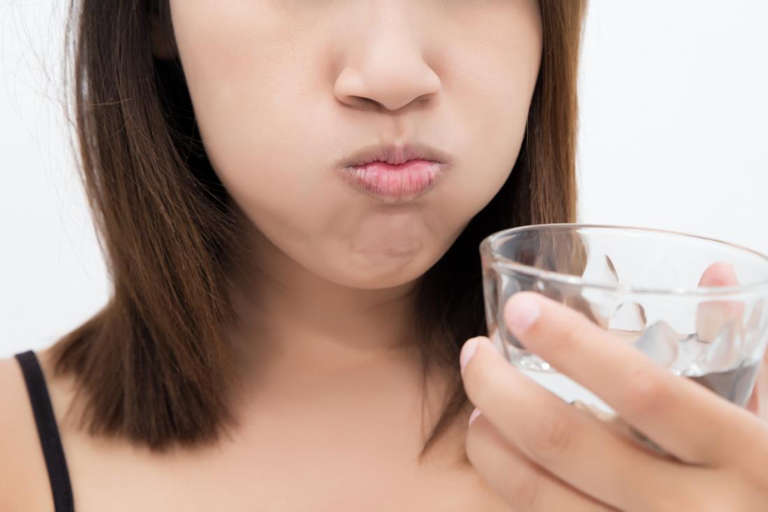 Woman gargling and rinsing her mouth with salt water.
