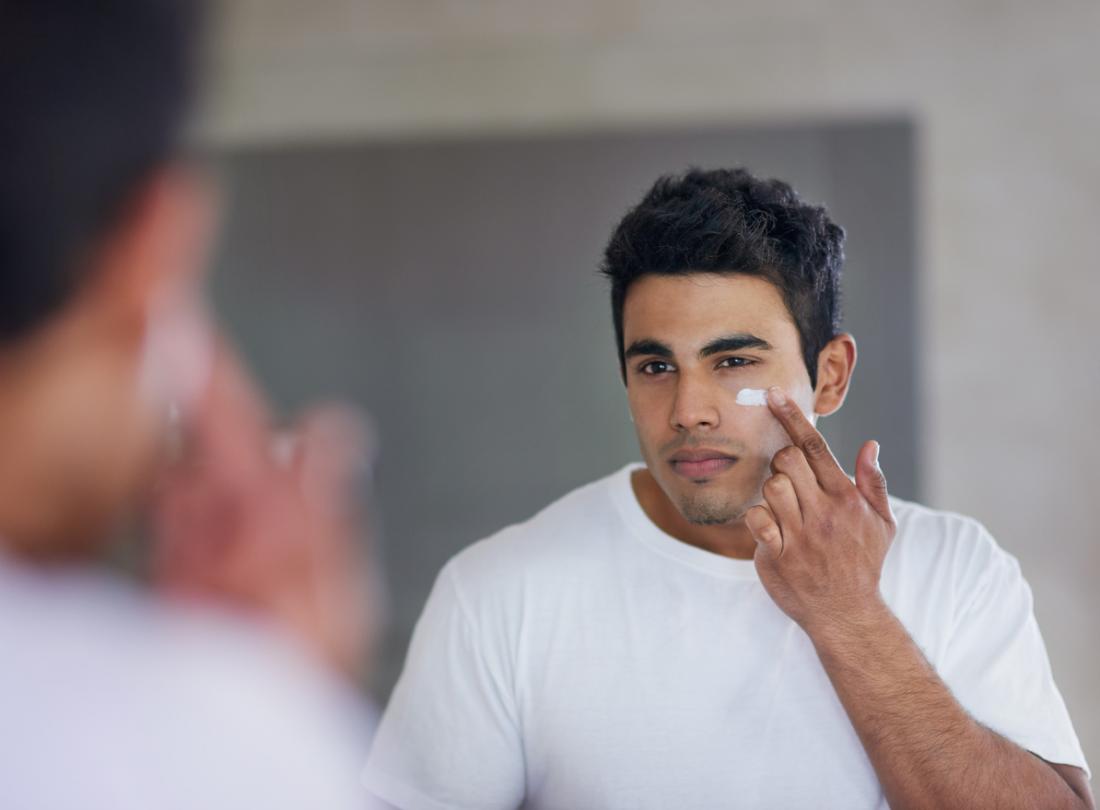 male using cream on his face