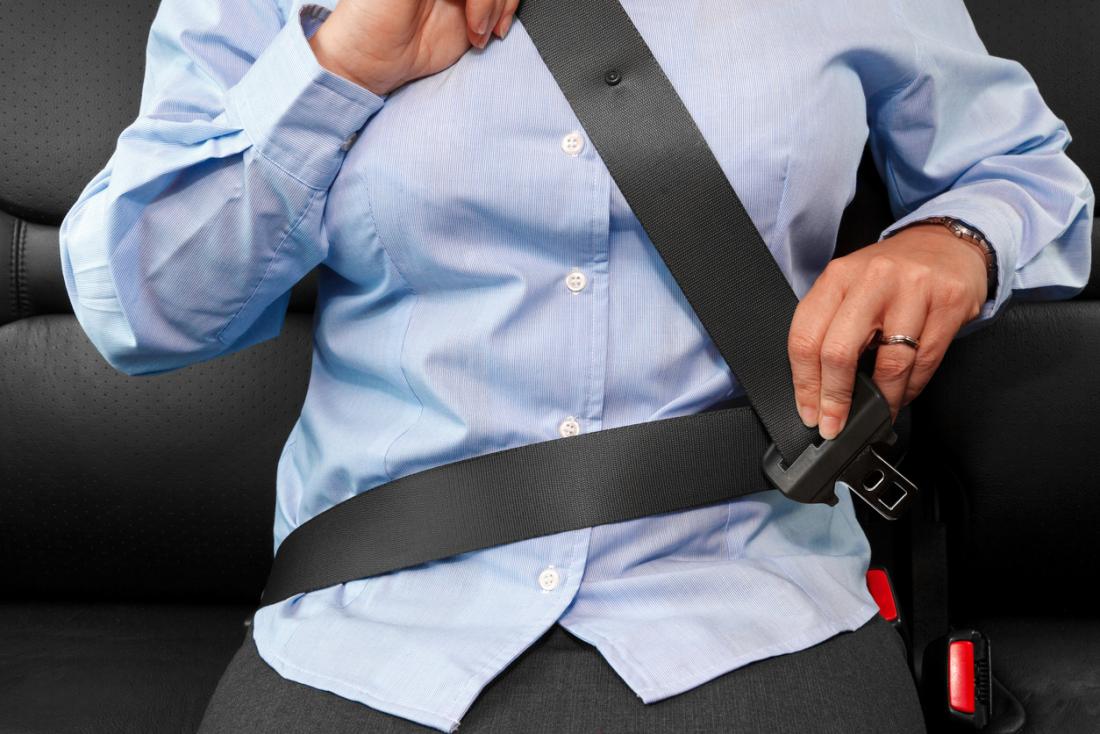 Woman strapping in her seatbelt across her chest.
