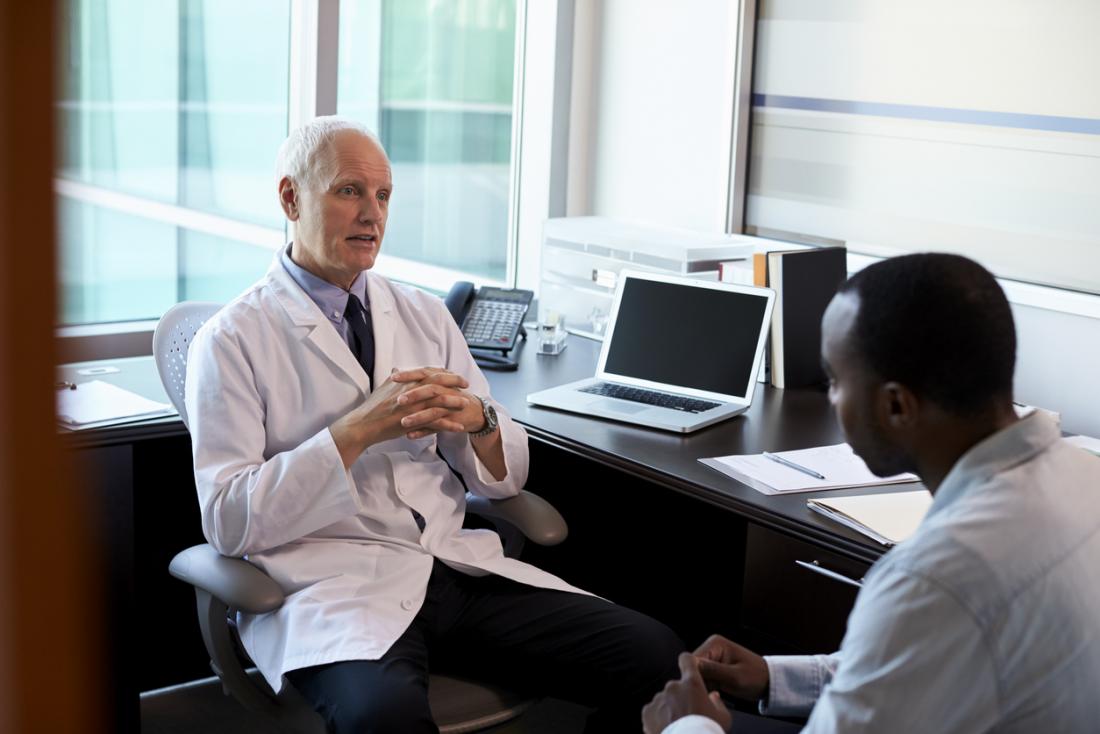 Senior white male doctor with young black male patient, in discussion.