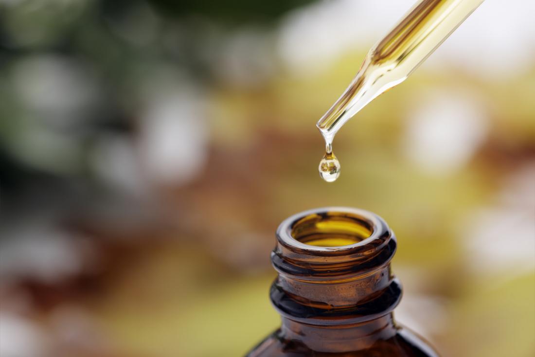 Dropper above essential oil bottle, with a drop falling back into the glass bottle.