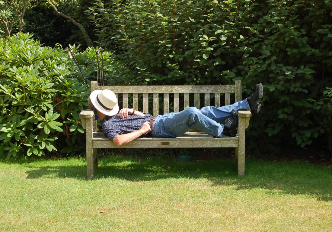 man having siesta on a bench in the shade