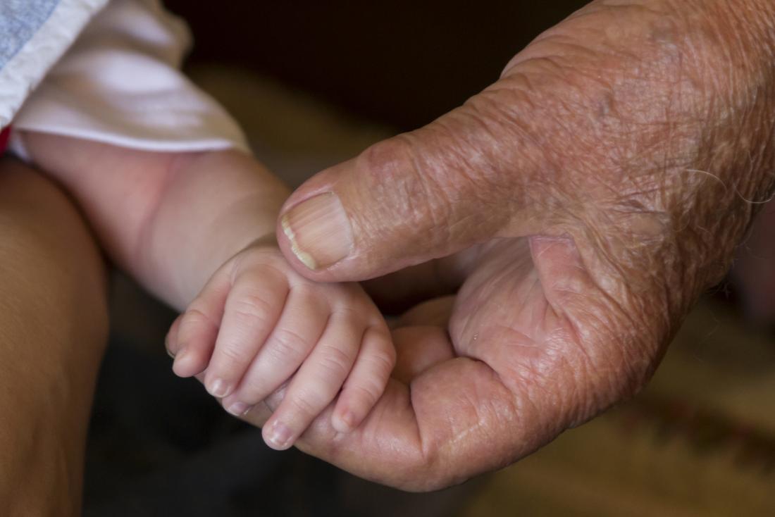 senior hand holding a babies hand
