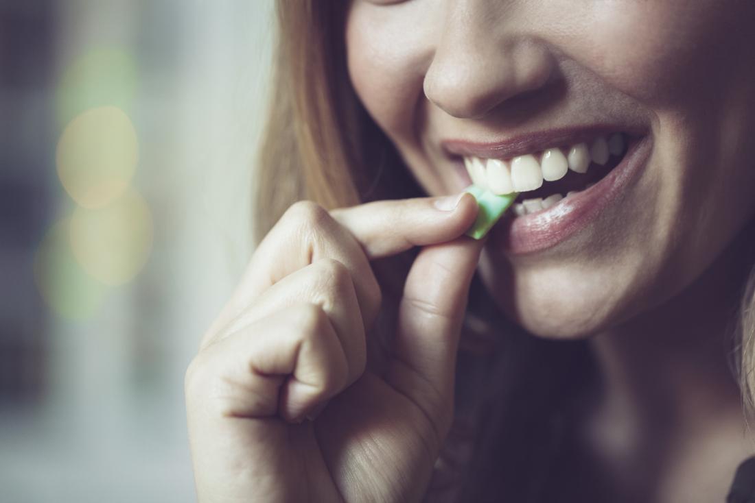 lady putting a piece of chewing gum in her mouth