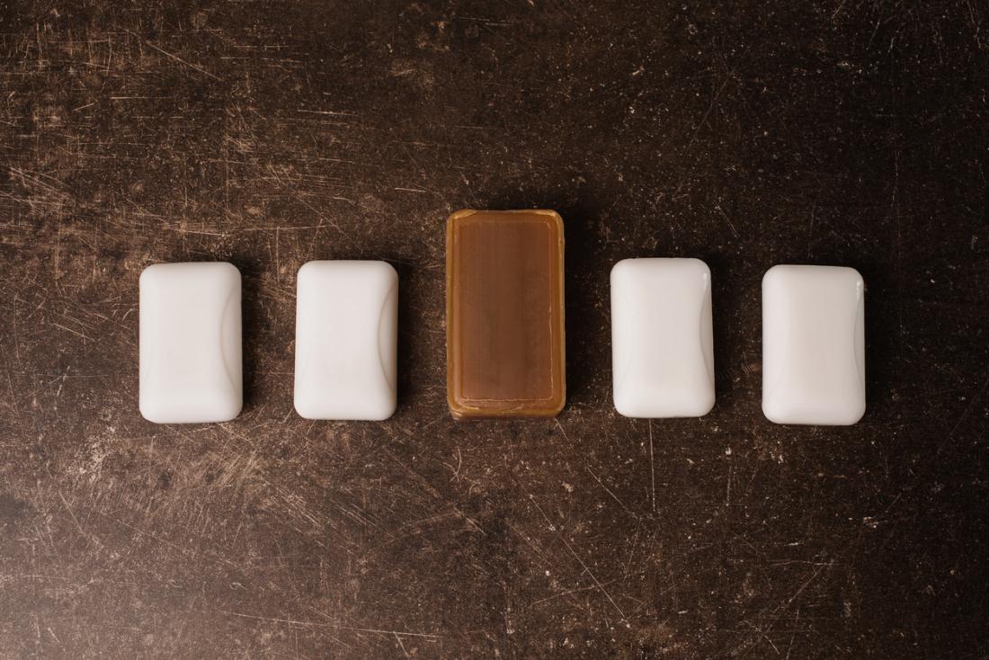 Four bars of white soap laid out, with one larger bar of tar soap in the middle.