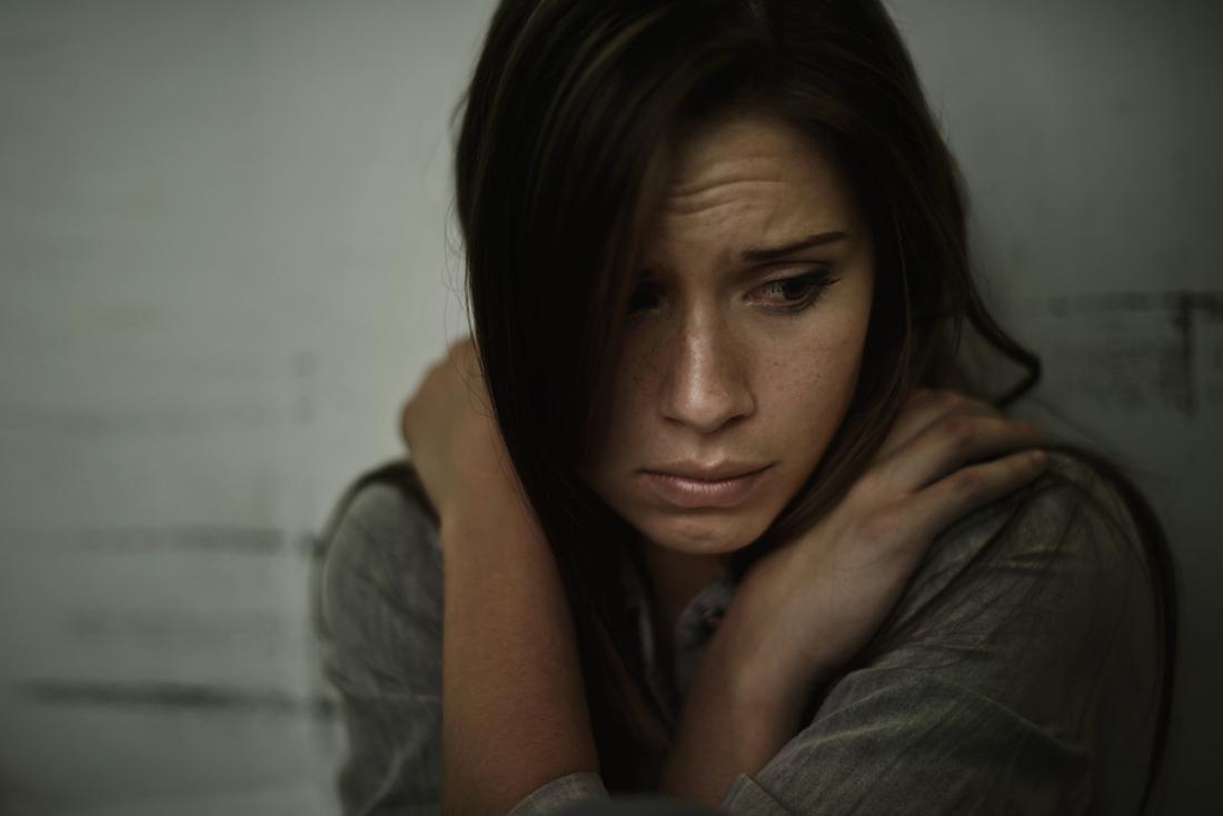 Stressed, anxious, and depressed woman holds her hands across her chest.