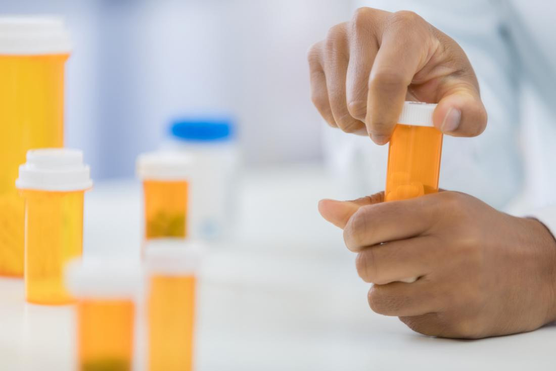 Pharmacist handling several yellow pill and medication bottles.