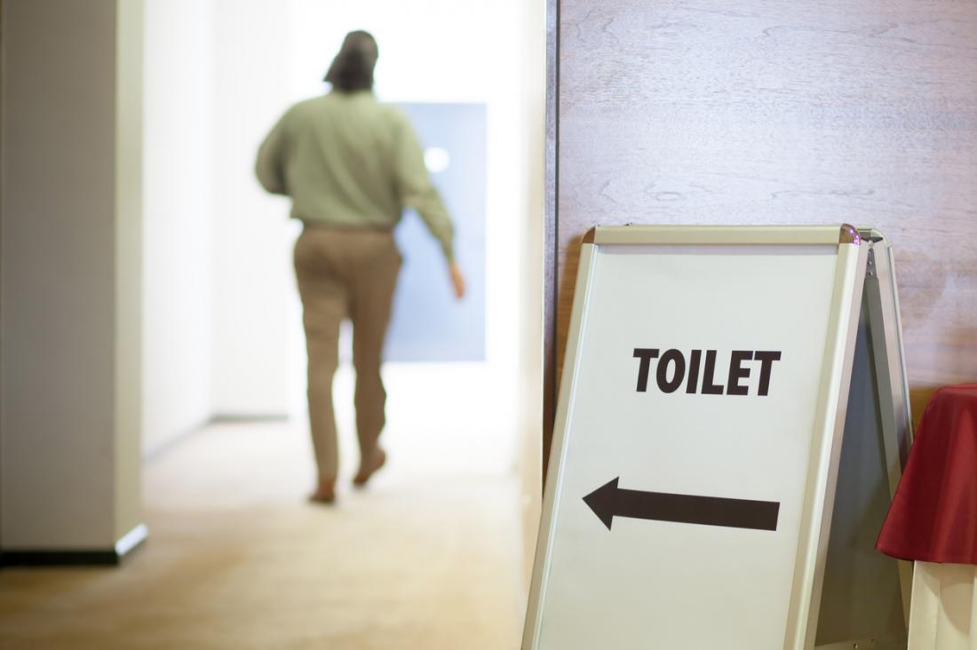 man in the background heading into a toilet