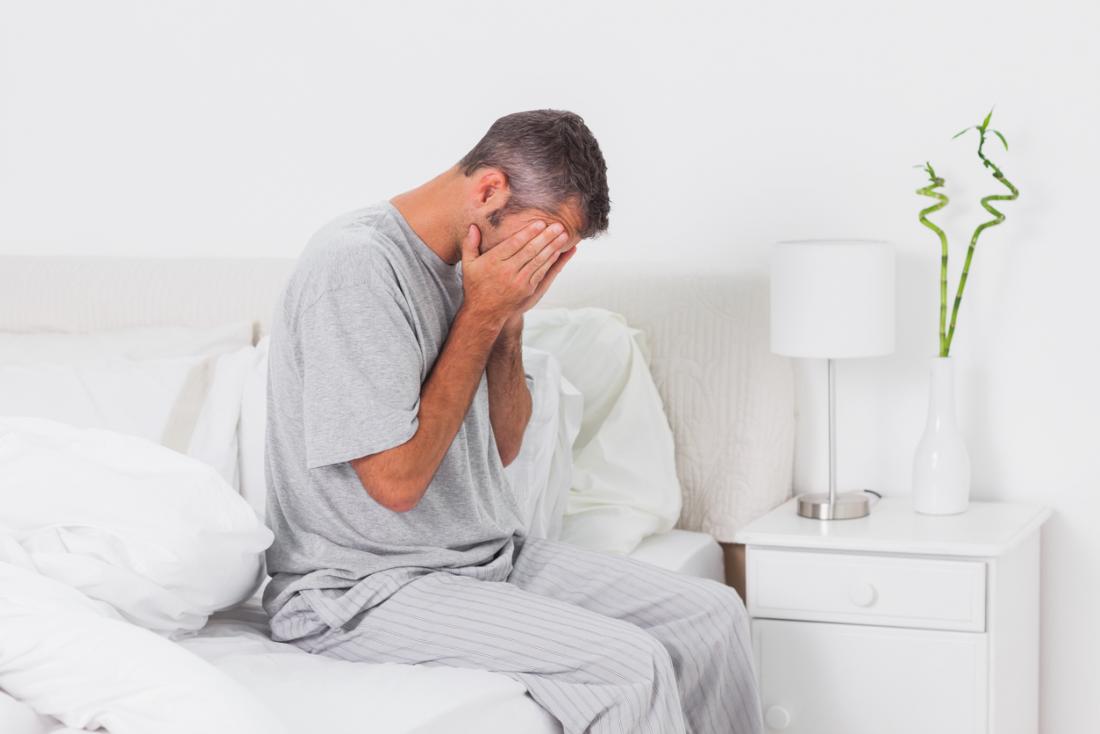 Anxious man sitting on his bed at home
