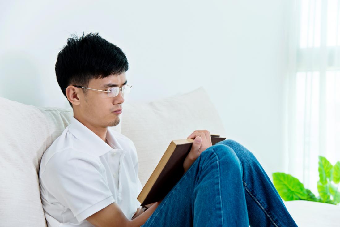 Young Asian man reading at home.