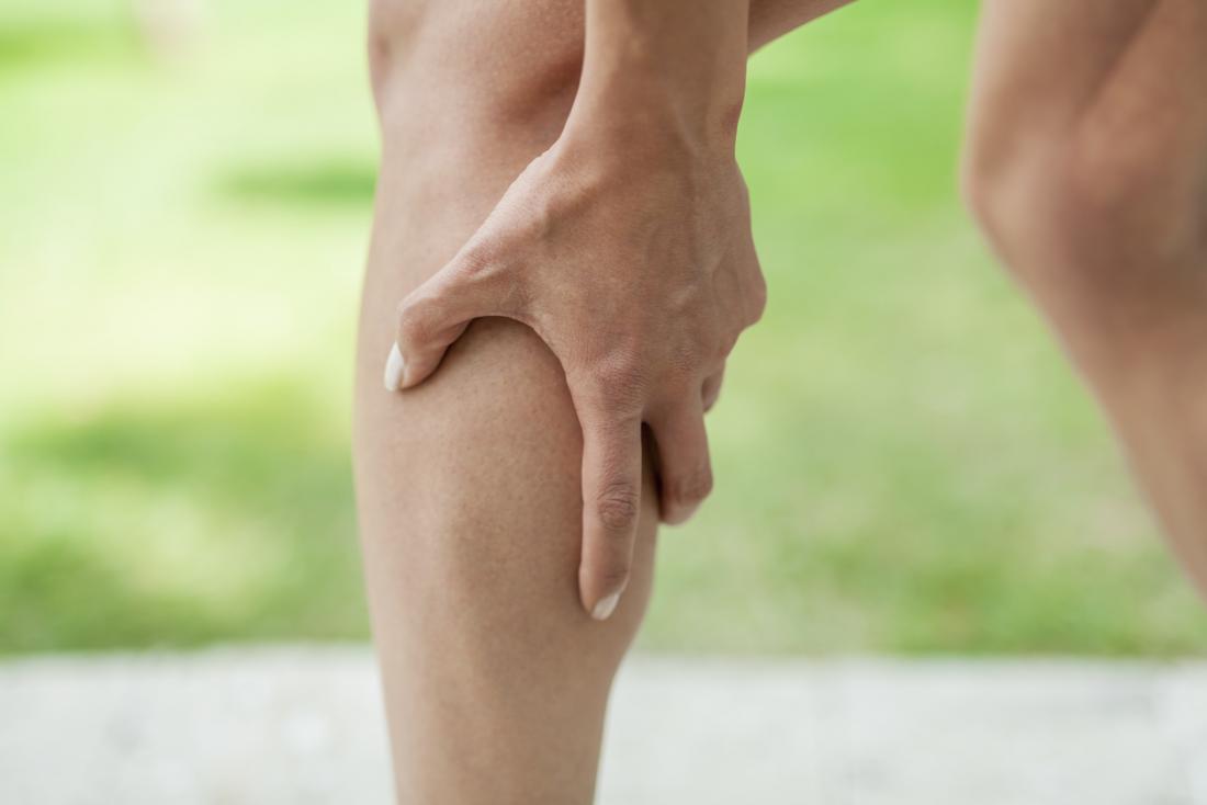 Person holding their calf in pain, experiencing a cramp.