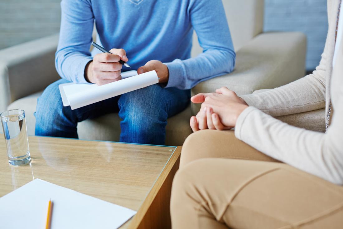 Counsellor in a therapy session with client, taking notes.