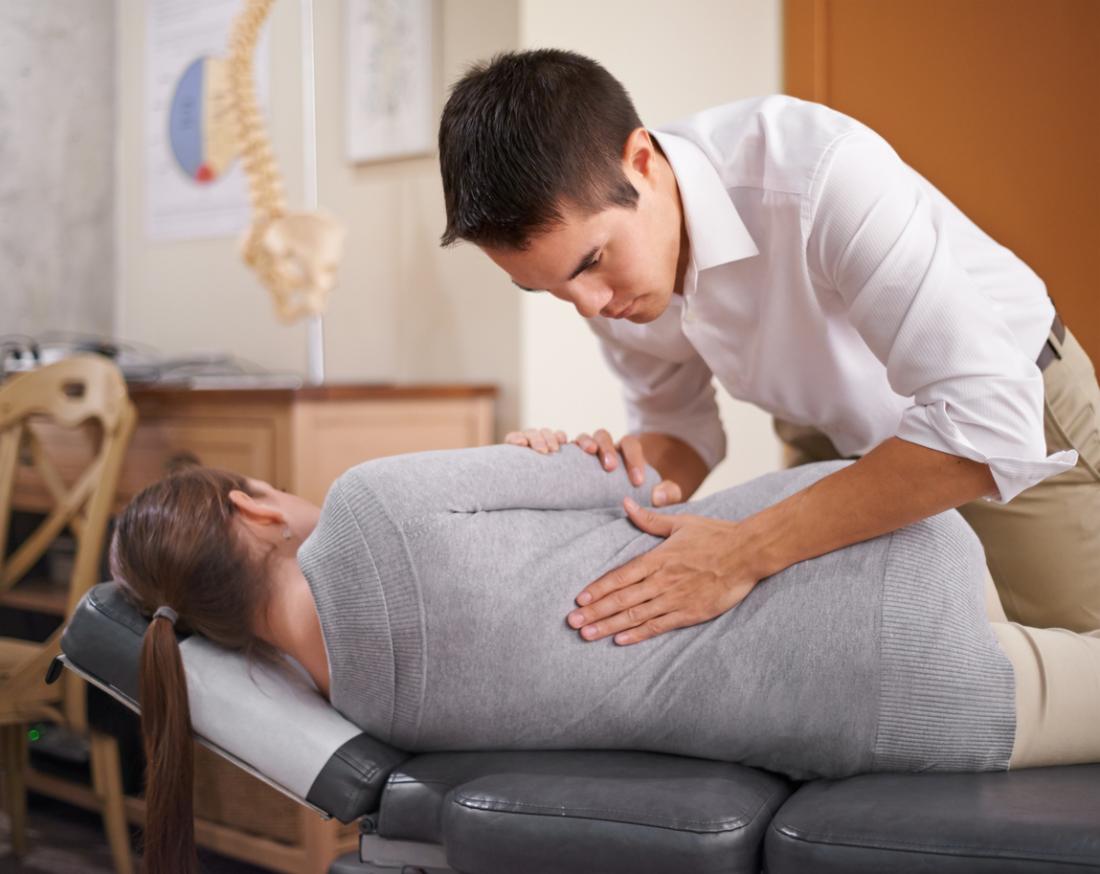chiropractor manipulating the back of a lady