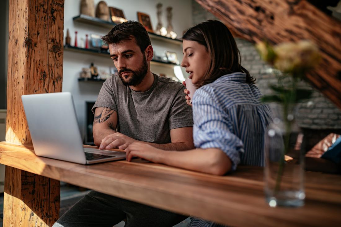 a couple sat at a computer.