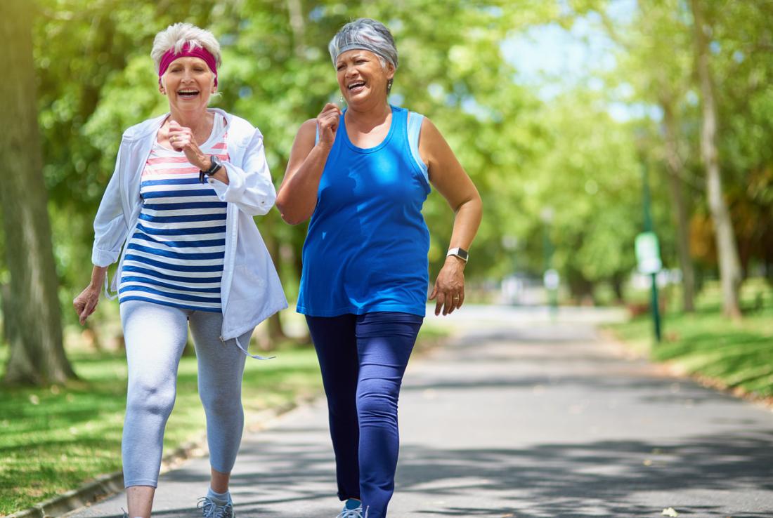 two middle aged women fitness walking through park